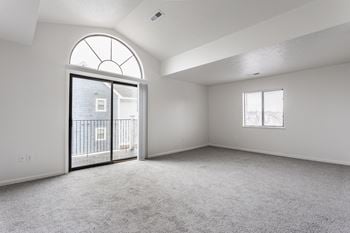 A spacious room with a large arched window and a sliding glass door leading to a balcony